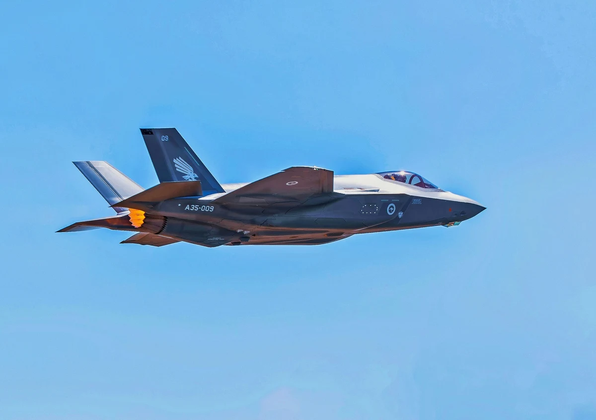 A military jet flying through a clear blue sky.